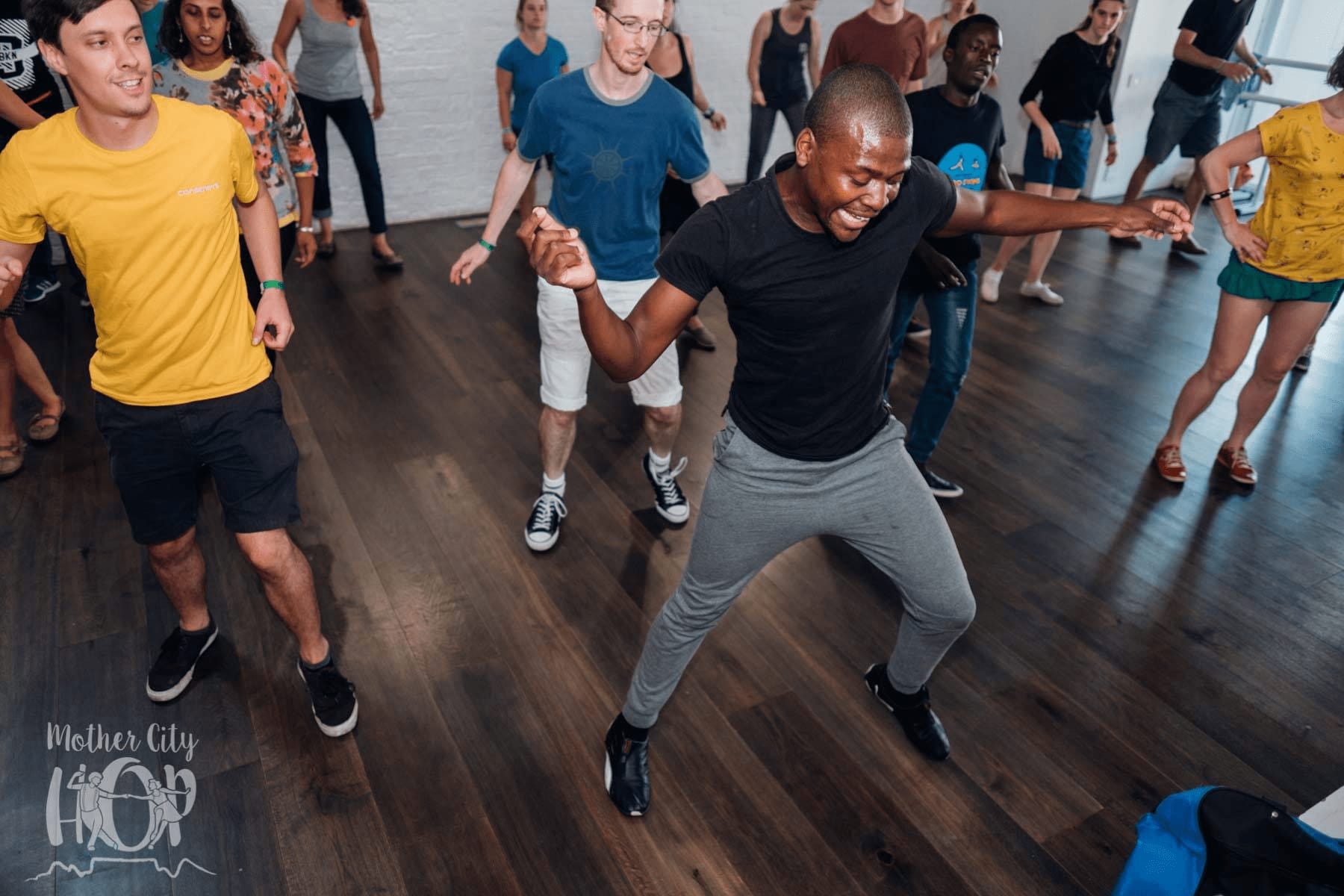 an image of a group of people dancing to the zavum in a studio and Elvis sibeko leading them 